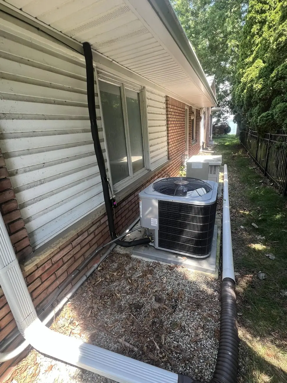 New AirQuest air conditioning condenser installed outside a brick home